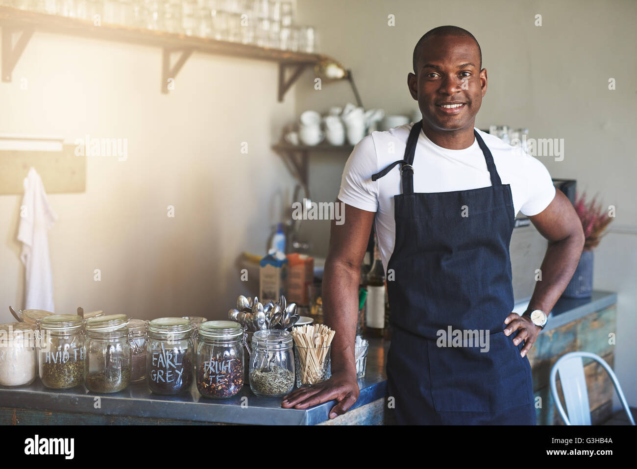 Schöne schwarze Unternehmer steht Café Zähler gesäumt Gläser Tee während des Tragens dunklen farbigen Schürze Stockfoto