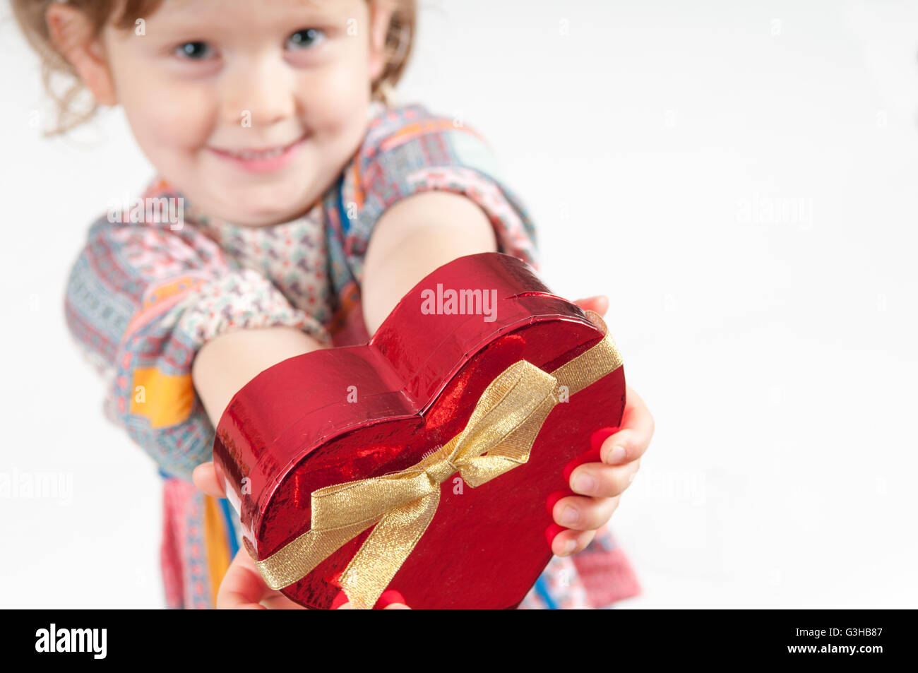 Junges Mädchen hält ein Geschenk verpackt Geschenk in Herzform Stockfoto