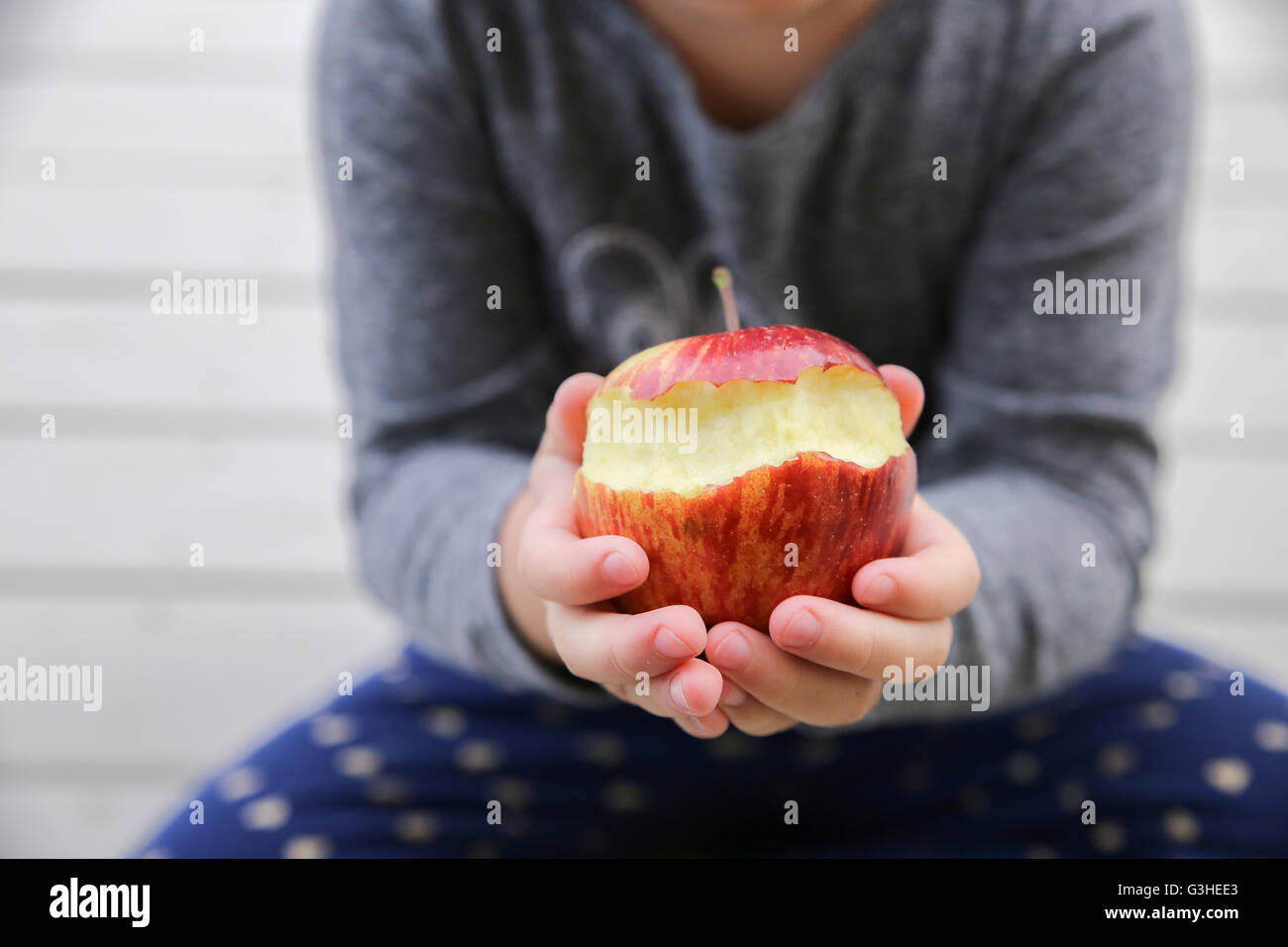 Kind Hände halten einen roten angebissene Apfel, einen Apfel pro Tag halten den Doktor fern, Gesundheitskonzept Stockfoto