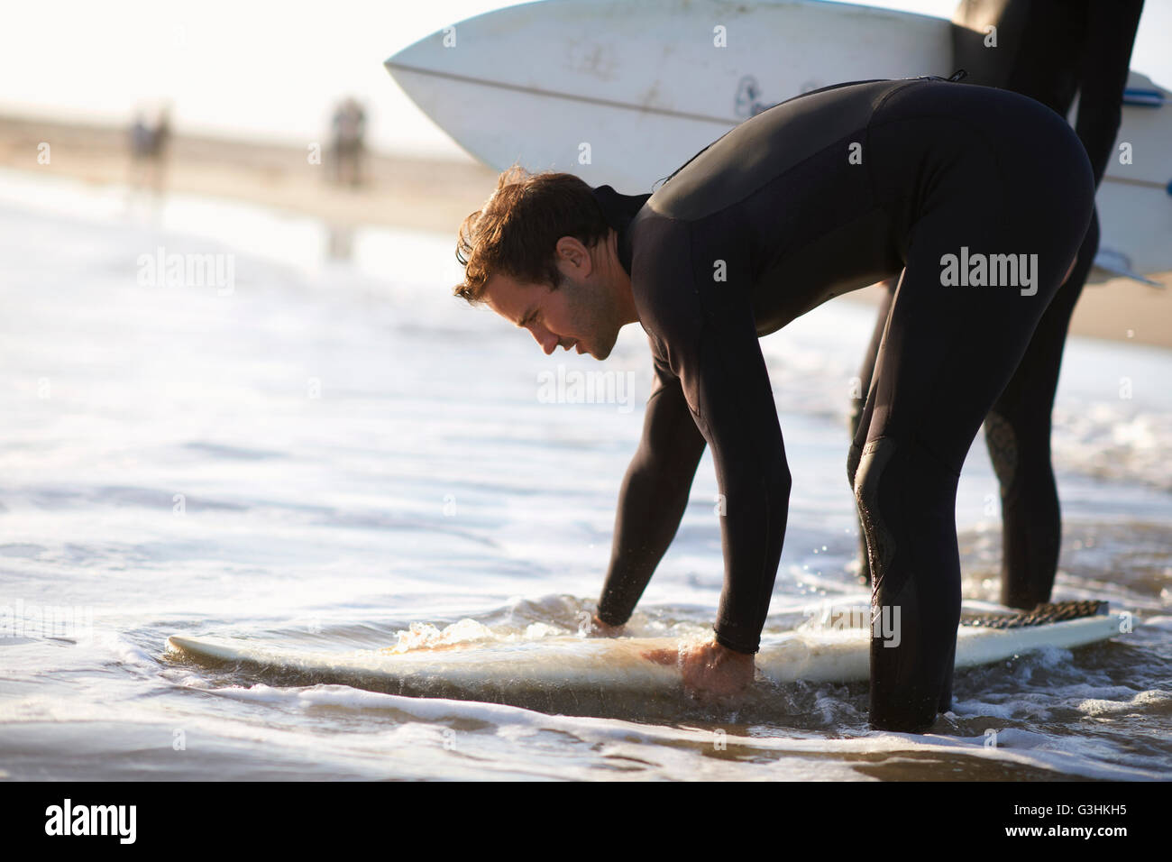 Männliche Surfer Vorbereitung Surfbrett im Meer am Venice Beach, Kalifornien, USA Stockfoto