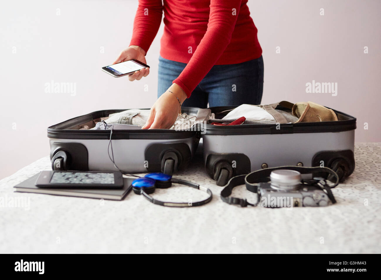 Frau packen Koffer, mit Smartphone, Mittelteil Stockfoto