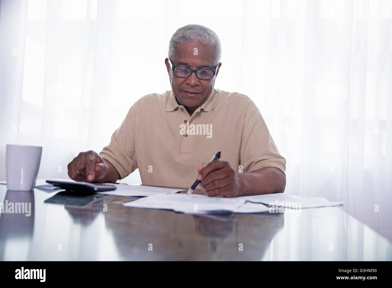 Senior Mann sitzt am Tisch, Papierkram zu tun Stockfoto