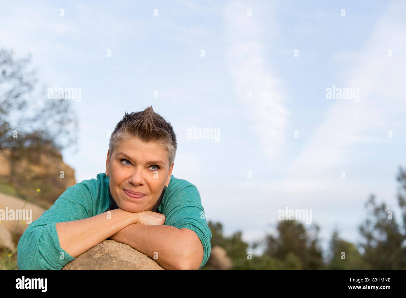 Porträt der Frau stützte sich auf Ellbogen gegen Felsen suchen Sie lächelnd Stockfoto