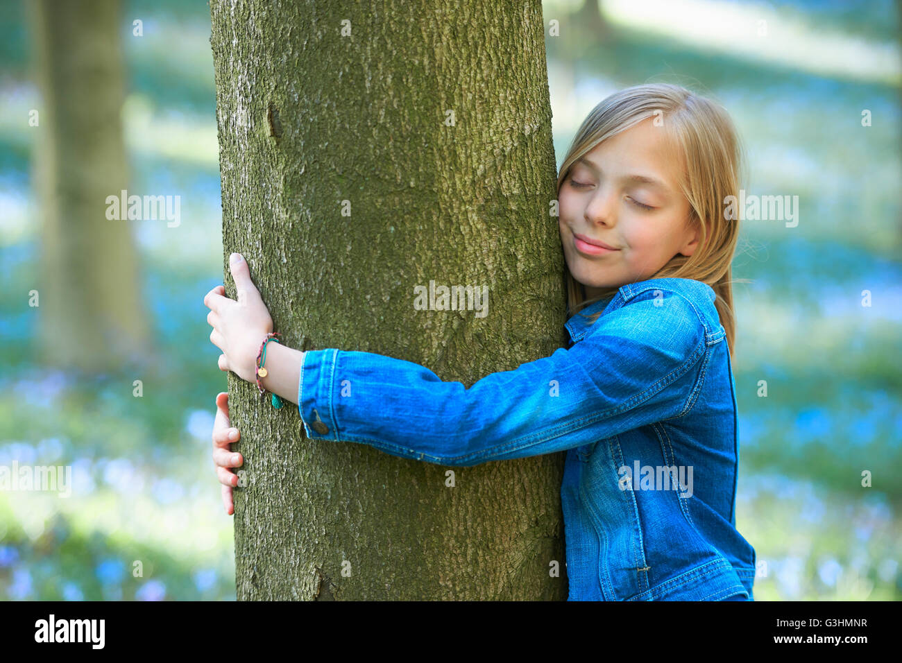 Mädchen umarmt Baum in Bluebell Wald, Hallerbos, Brüssel, Belgien Stockfoto
