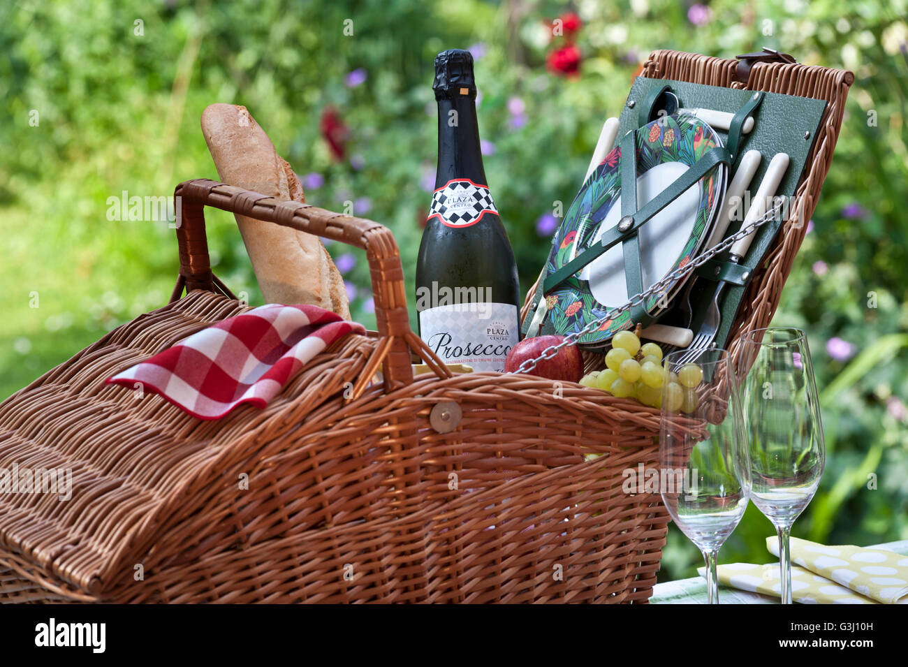 Prosecco Wein Flasche und Wicker Picknick-Korb in sonniger blumigen Garten Lage Stockfoto