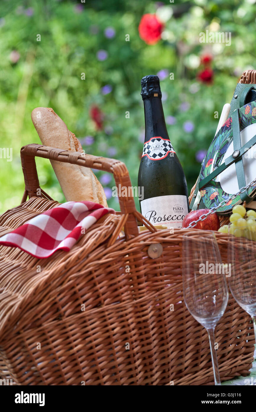 Prosecco Wein Flasche und Wicker Picknick-Korb in sonniger blumigen Garten Lage Stockfoto