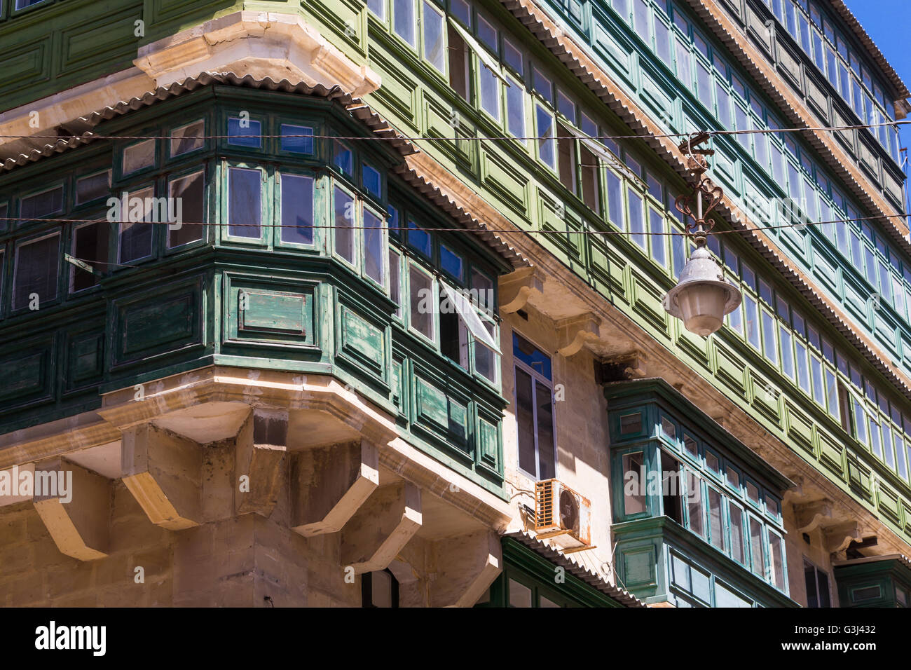 Ecke eines Hauses in der Hauptstadt der Insel Malta - Valletta. Typischen Balkonen und vielen Fenstern. Straßenlaterne im Vordergrund. Stockfoto