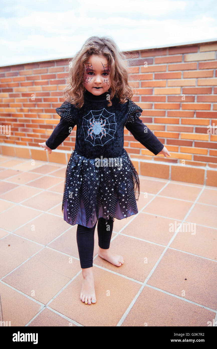 kleines Mädchen mit Spinnennetz gemalt auf Gesicht, Blick in die Kamera. Halloween Stockfoto
