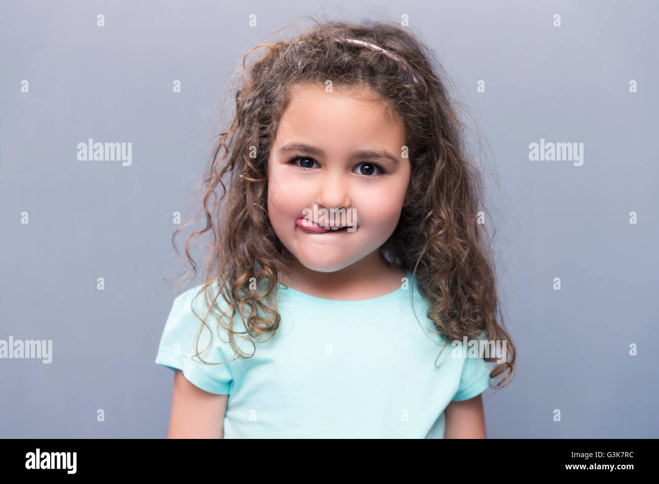 Porträt von schönen Mädchen mit dem lockigen Haar, Blick in die Kamera während der Zunge. Studio gedreht Stockfoto