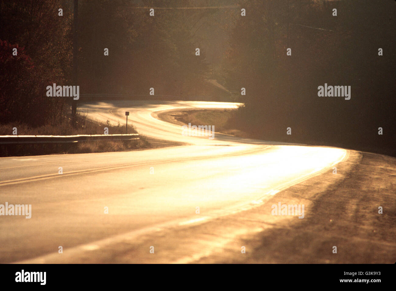 kurvenreiche Straße durch die untergehende Sonne beleuchtet Stockfoto