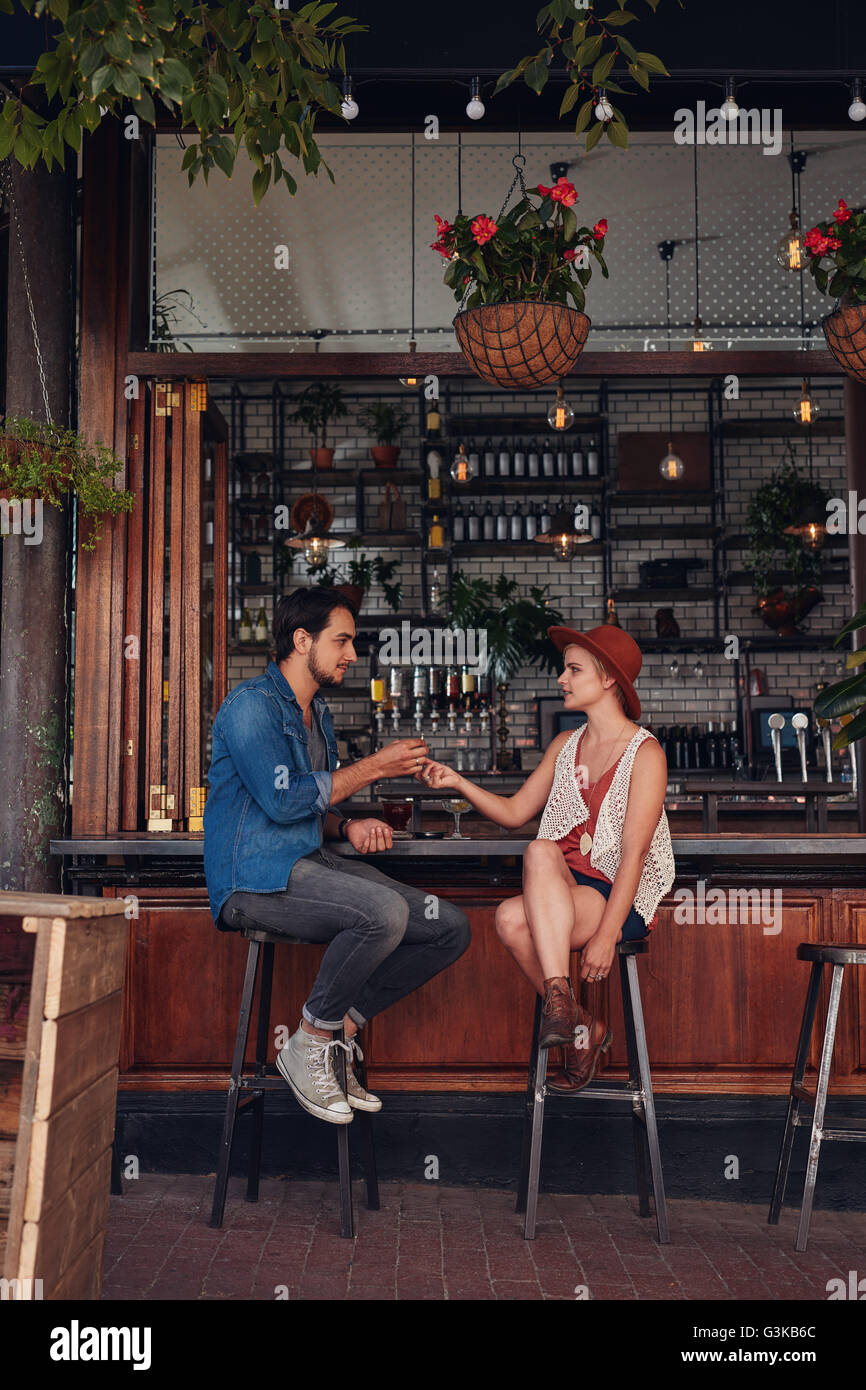 Voller Länge Schuss junges Paar sitzt am Café-Schalter. Junger Mann und Frau teilen Zigarette im Coffee Shop. Stockfoto