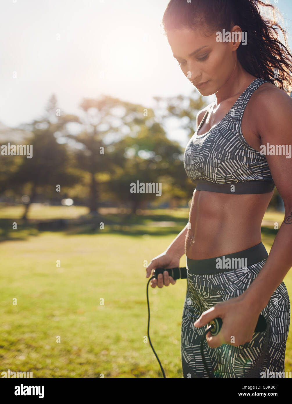 Schuss von Fitness-Frau, die das Training mit dem Springseil in einem Park. Gesunde weibliche tun Training im Freien an einem sonnigen Tag überspringen. Stockfoto