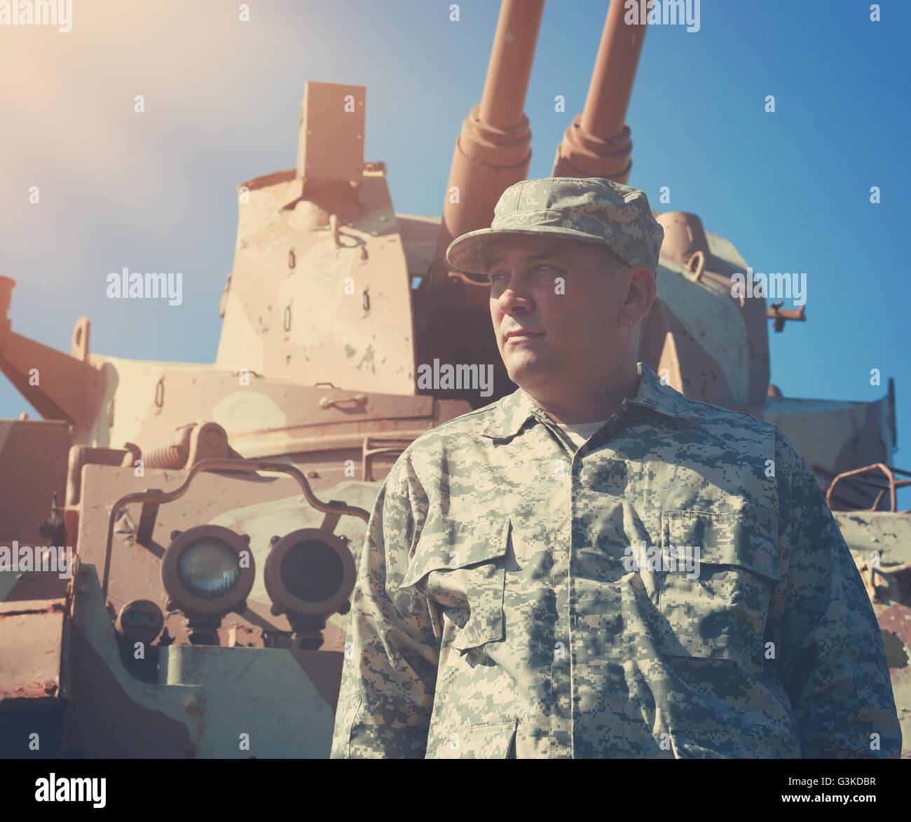 Ein militärischer Soldat steht vor einer Armee Tankfahrzeug mit Sonne draußen für einen amerikanischen Krieg, Verteidigung oder Sicherheit Freihafengelände Stockfoto