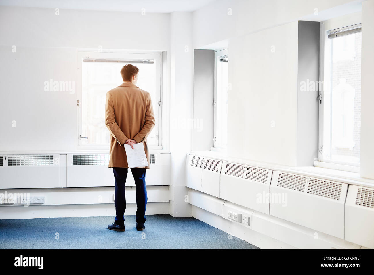 Rückansicht des Mannes in leeres Büro, Hände hinter Rücken Blick aus Fenster Stockfoto