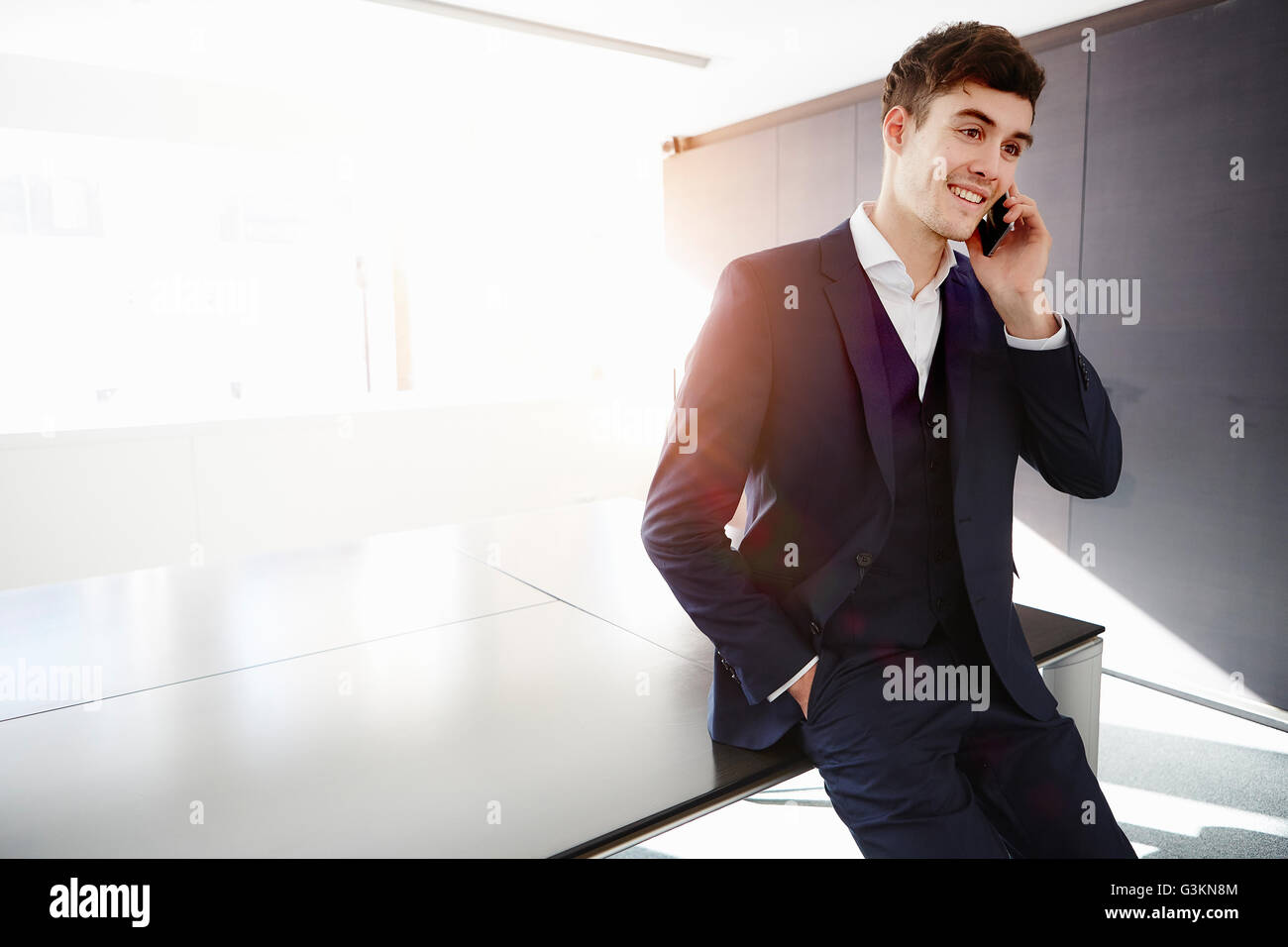 Mann, sitzend am Schreibtisch machen Telefongespräch Lächeln Stockfoto