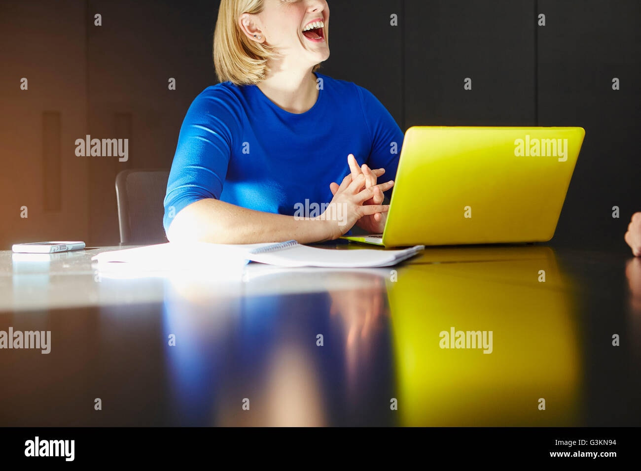 Blick auf Frau sitzt am Schreibtisch mit Laptop Computer Lachen beschnitten Stockfoto