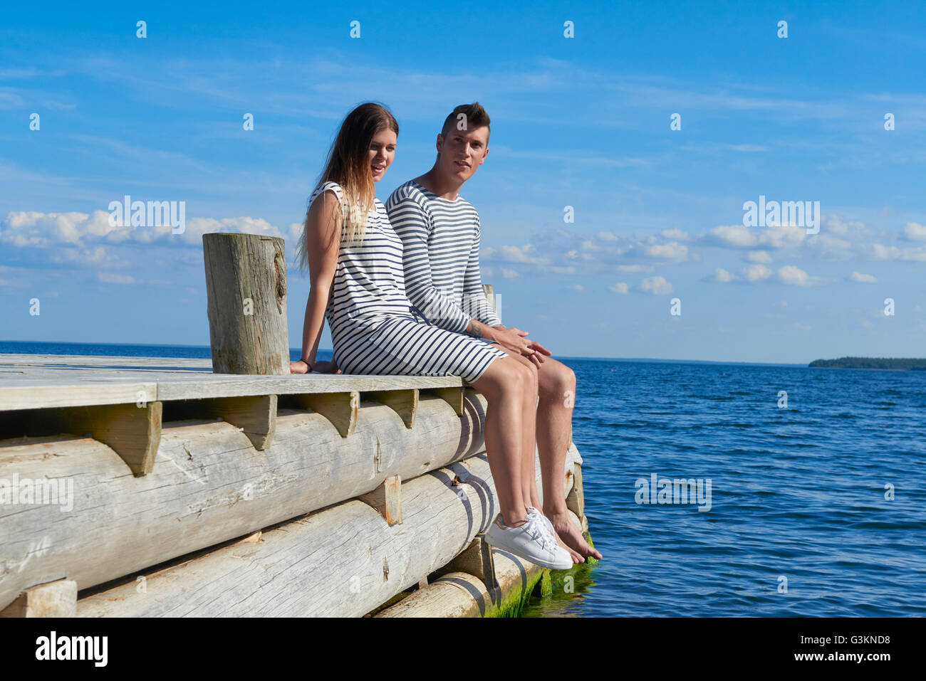 Junges Paar auf Holzsteg sitzen, relaxen Stockfoto