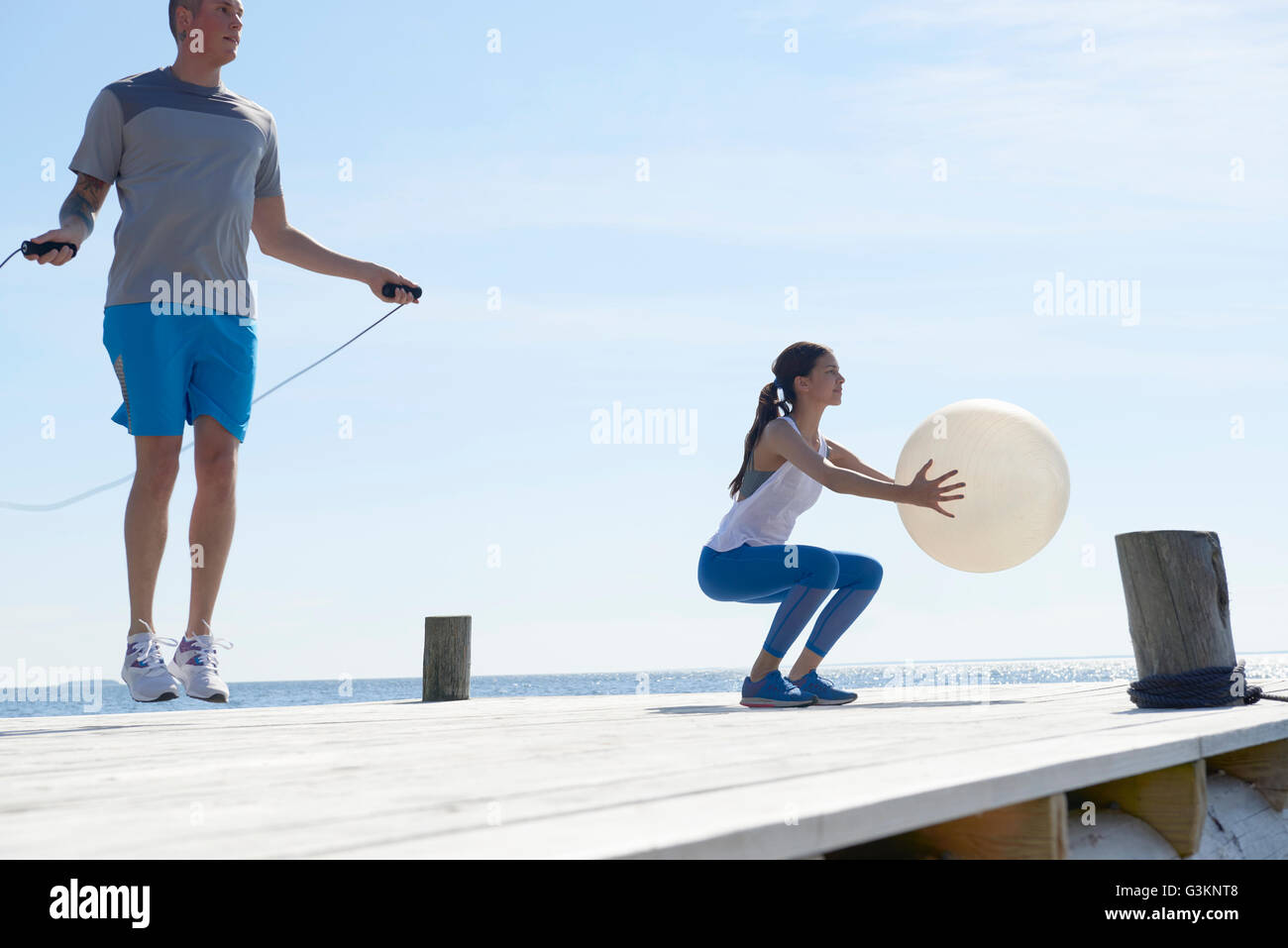 Paar am Pier mit Springseil und Gymnastikball Stockfoto
