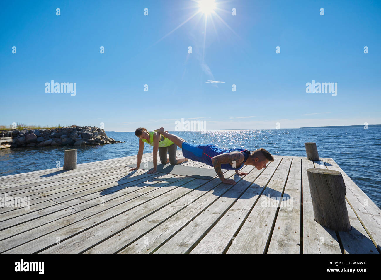 Mann am Pier dabei drücken ups, Beine angehoben auf Freund Stockfoto
