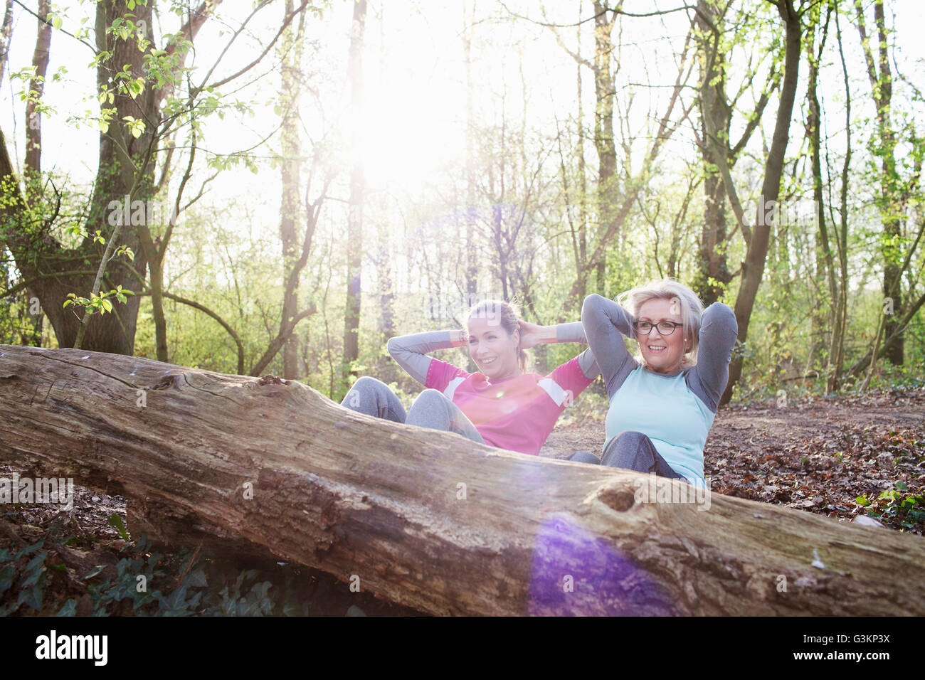 Frauen im Wald Hände hinter Kopf tun Sit up gegen umgestürzten Baum Stockfoto