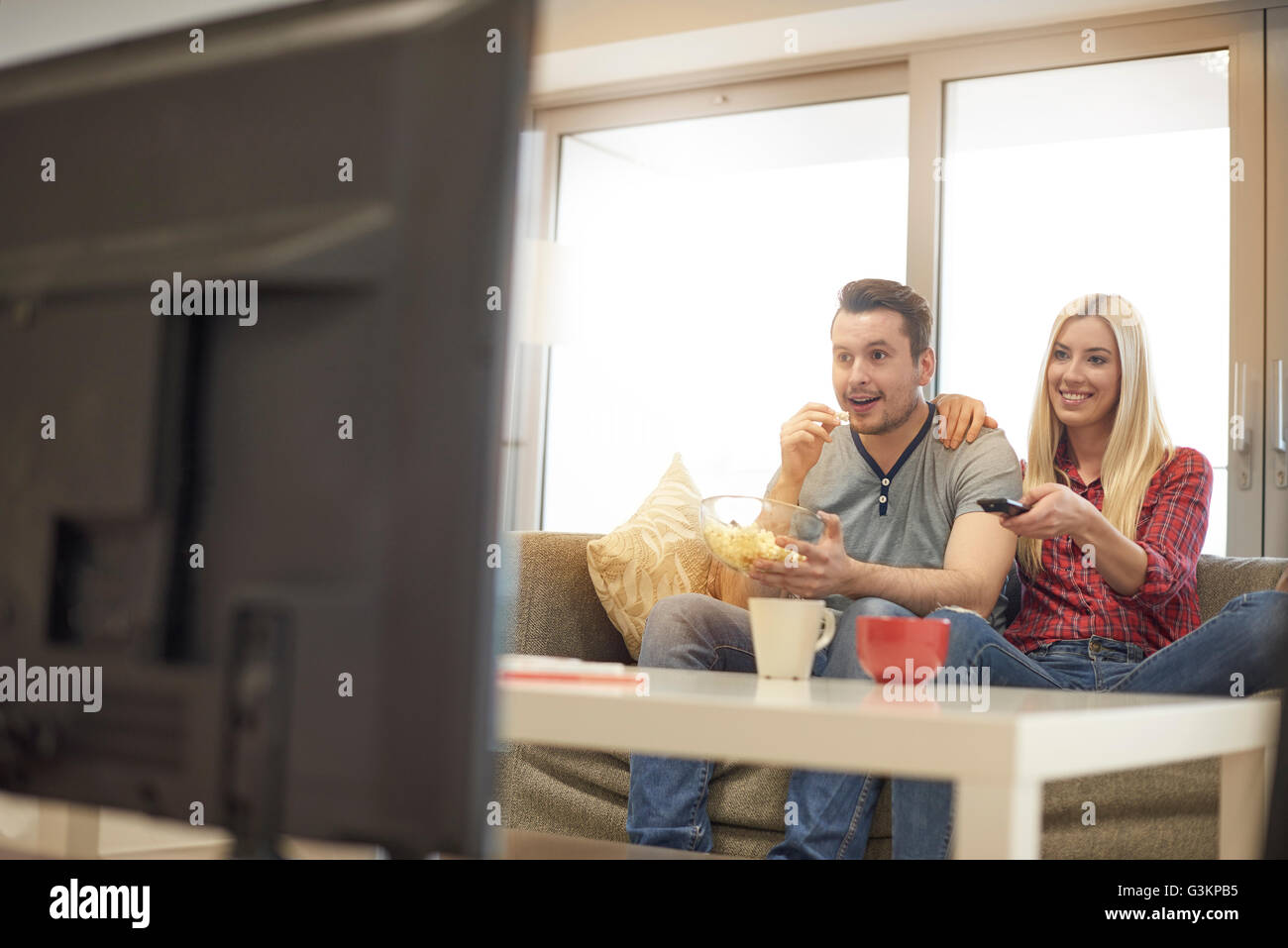 Junges Paar zu Hause auf Sofa, Fernsehen, aufgeregt Stockfoto
