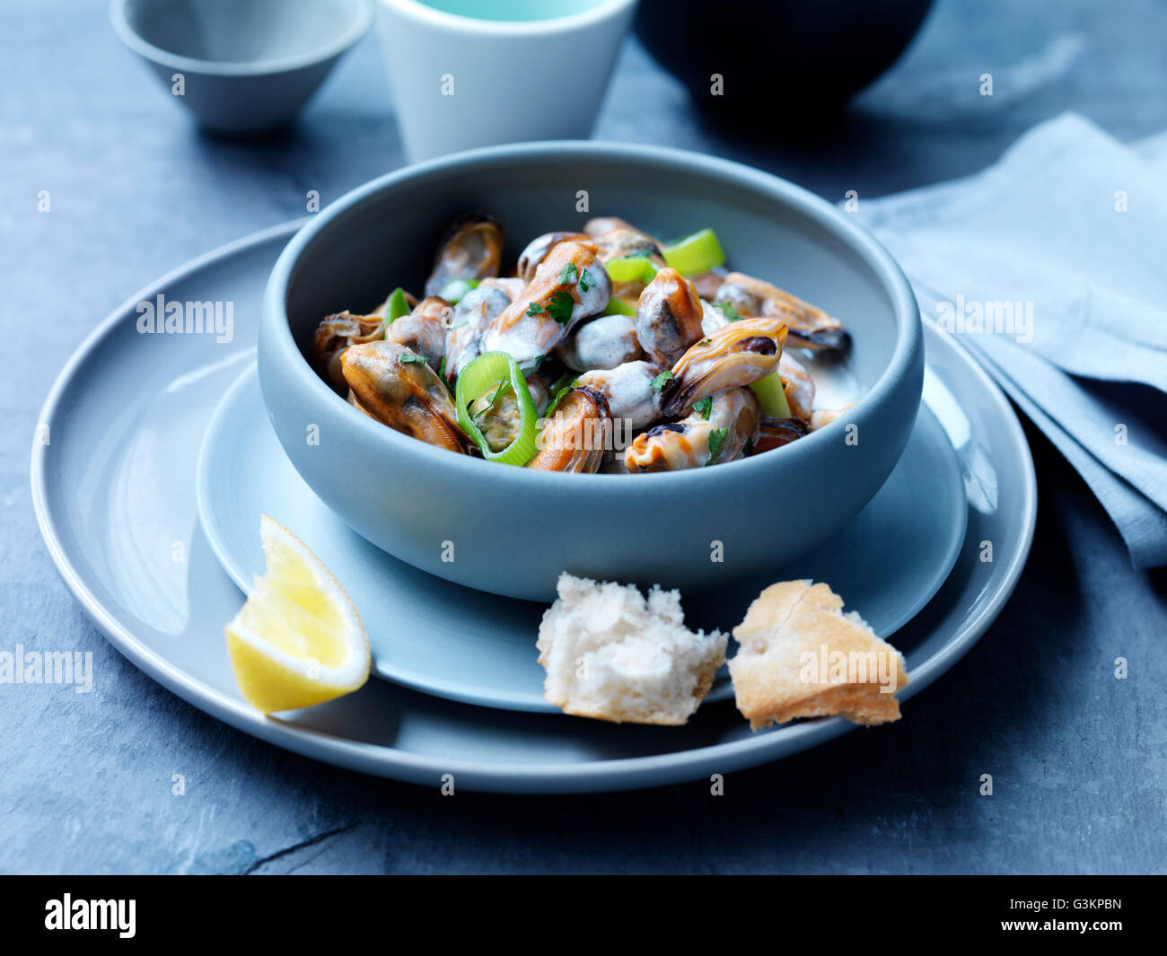 Muscheln, Lauch, Sauce und Kräuter in Schüssel mit Zitronenscheibe Stockfoto