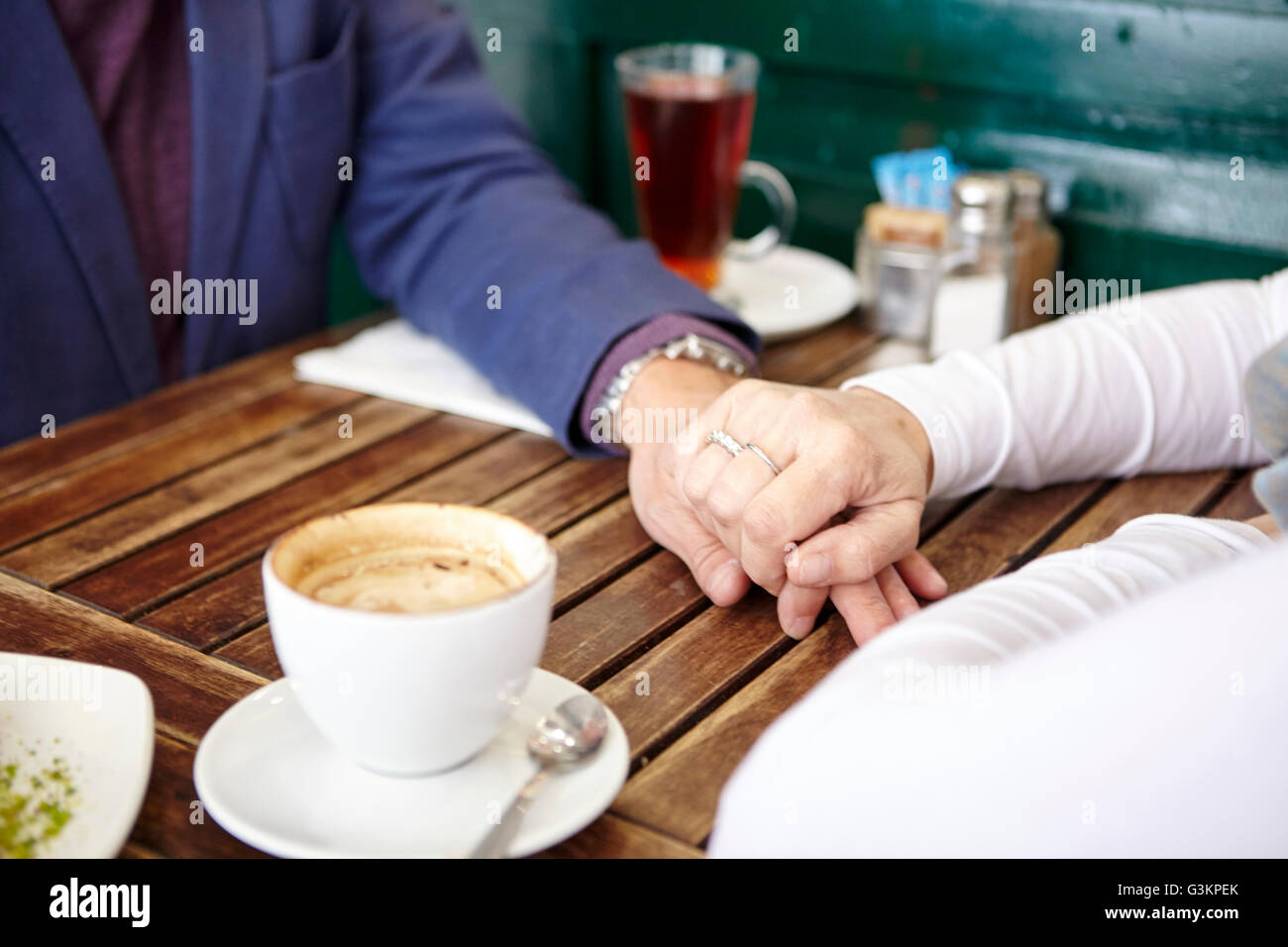 Nahaufnahme von Reife dating paar Hand in Hand am Bürgersteig Café-Tisch Stockfoto