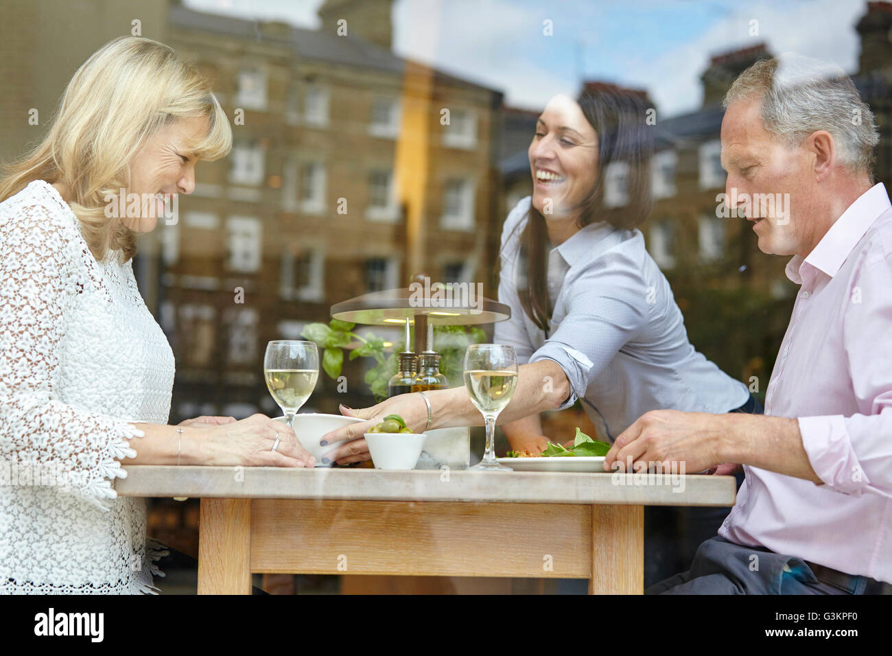 Kellnerin serviert Mittagessen Reifen dating paar am Tisch im Restaurant, London, UK Stockfoto
