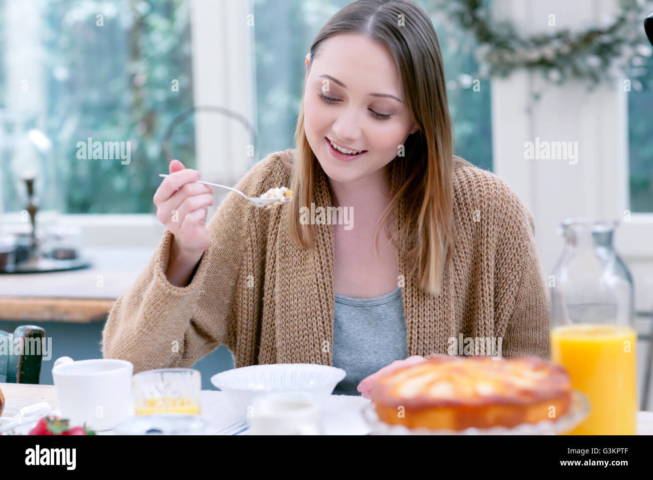 Frau sitzt am Tisch blickte lächelnd zu frühstücken Stockfoto