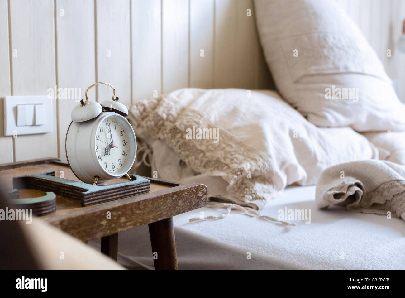 Ungemachten Bett, Wecker auf dem Nachttisch Stockfoto