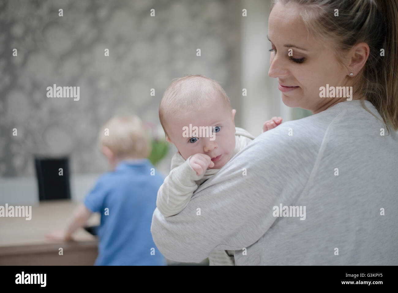 Mutter Babyjungen, älteren Sohn Tisch stand halten Stockfoto