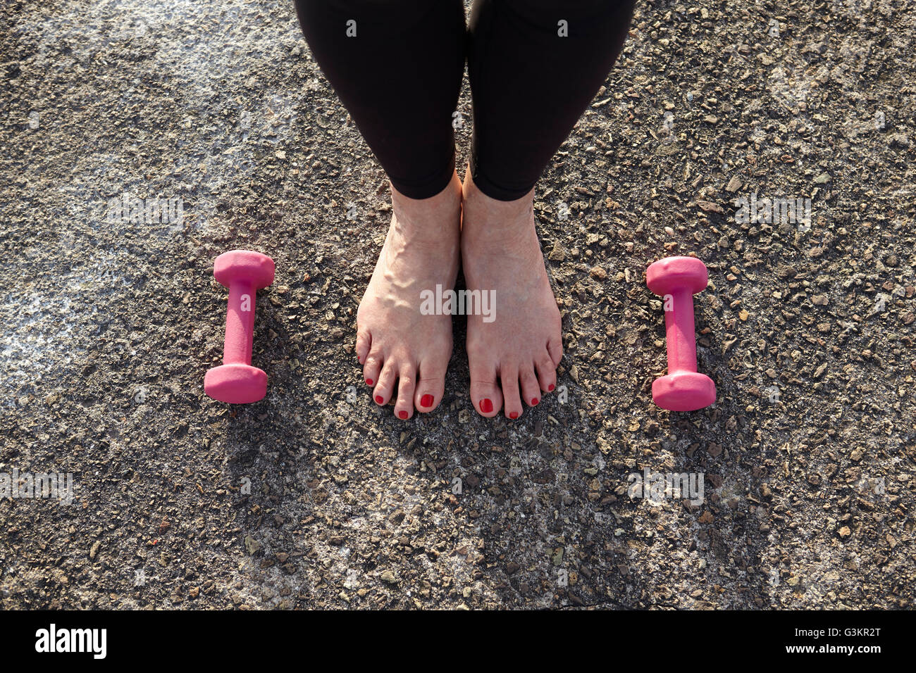 Reife Frau, barfuß, Hand Gewichte am Boden neben ihr, erhöht, Ansicht,  Schwerpunkt Con Füße Stockfotografie - Alamy