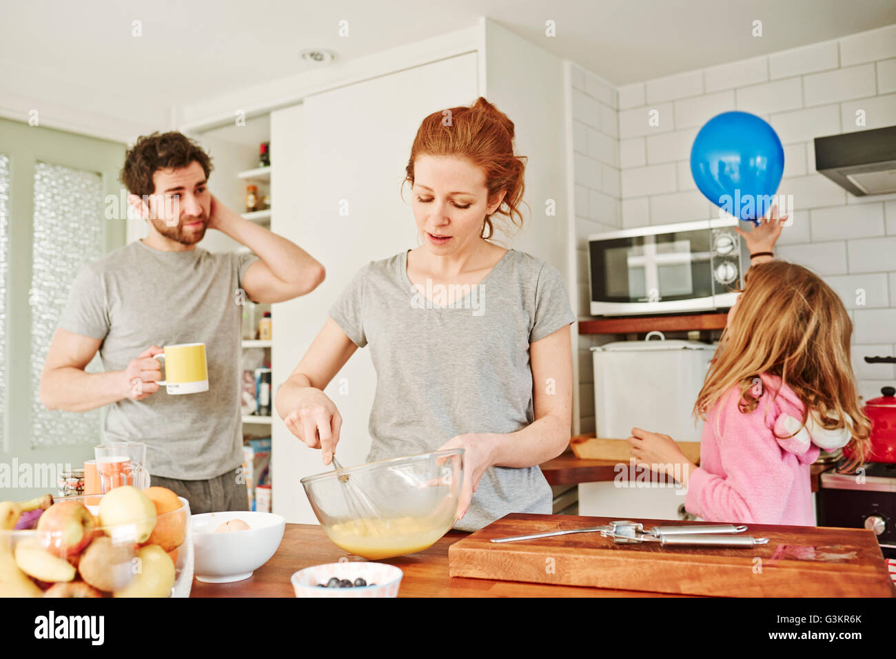 Mitte Erwachsene Frau schlagen von Eiern am Küchentisch für Frühstück mit der Familie Stockfoto