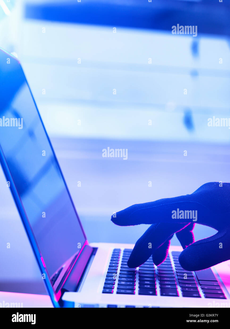 Behandschuhte Hand tippen und Laptop-Computer-hacking Stockfoto