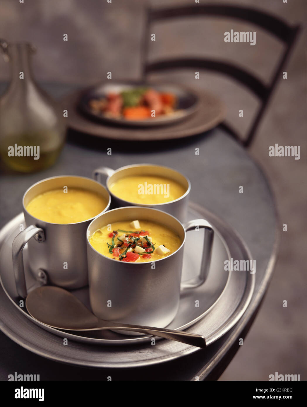 Gelbe Paprika Suppe mit Tomaten, Feta-Käse und Kräutern garnieren in Metallschalen Stockfoto
