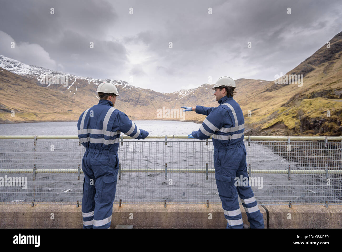 Arbeitnehmer auf Damm am Wasserkraftwerk mit Wasser Stockfoto