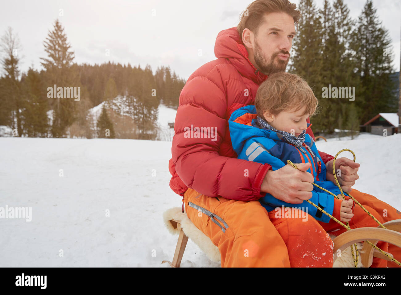 Junger Mann und Sohn Rodeln im Schnee, Elmau, Bayern, Deutschland Stockfoto