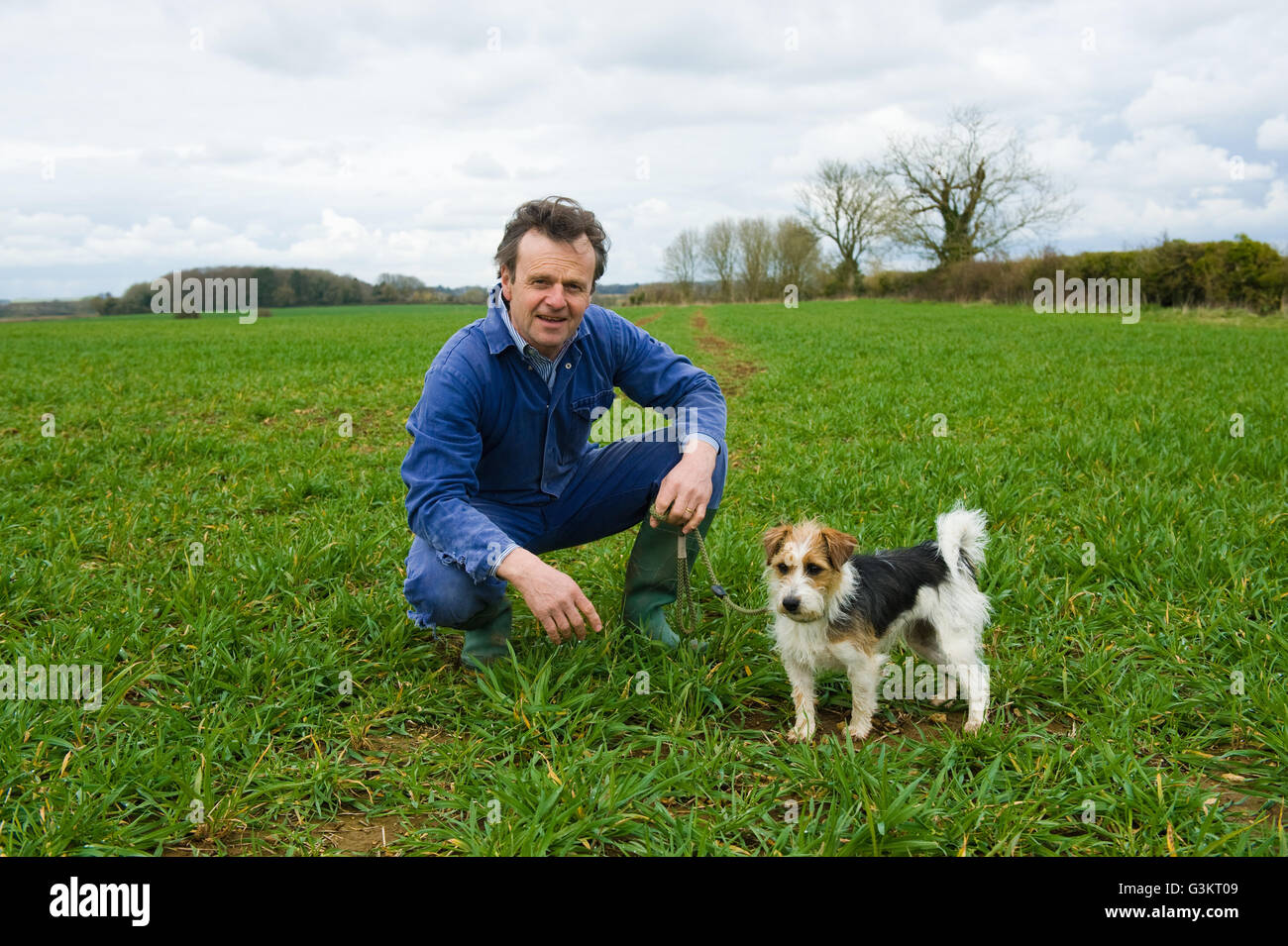 Porträt von Bauer hockend in Feld mit Hund Stockfoto