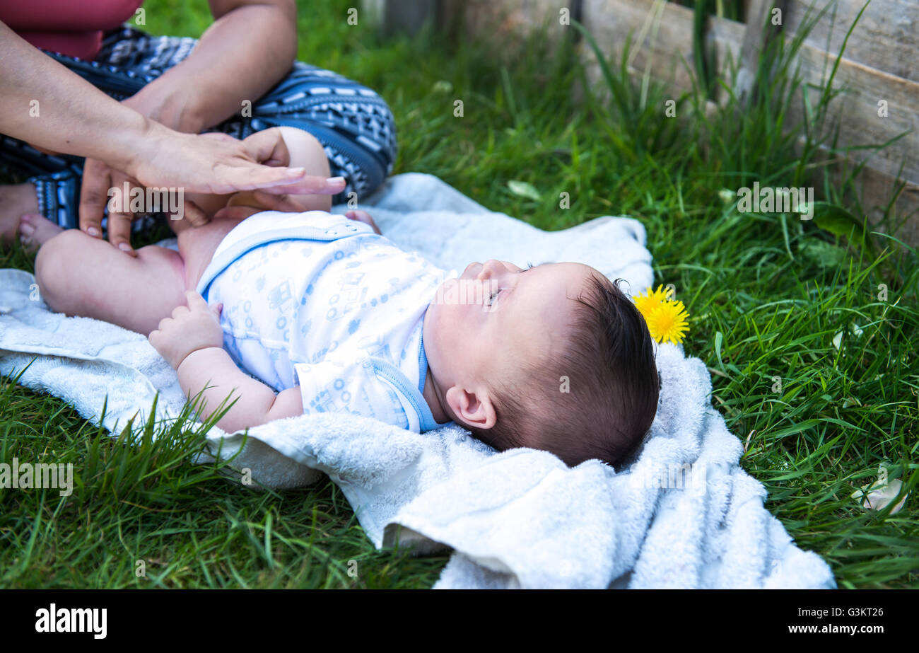 Zugeschnittene Aufnahme Frau Auftragen der Creme während Baby Sohn Windel im Garten ändern Stockfoto