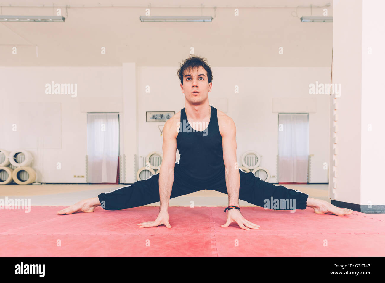 Mann Beine öffnen, ruht auf den Händen tun Bein stretching-Übungen Stockfoto
