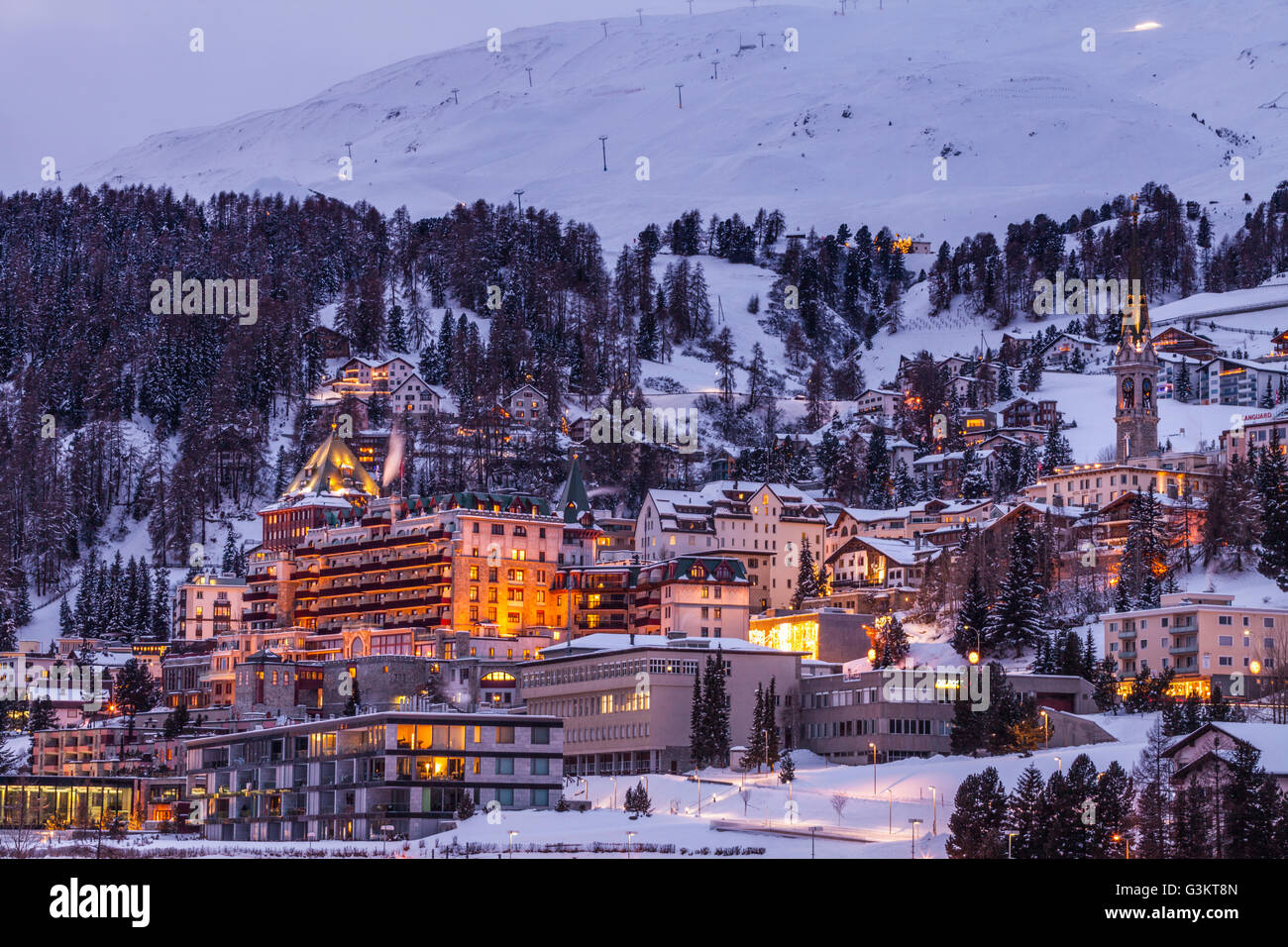 Dorf unter Berg auf verschneite Landschaft beleuchtet am Abend, Sankt Moritz, Schweiz Stockfoto