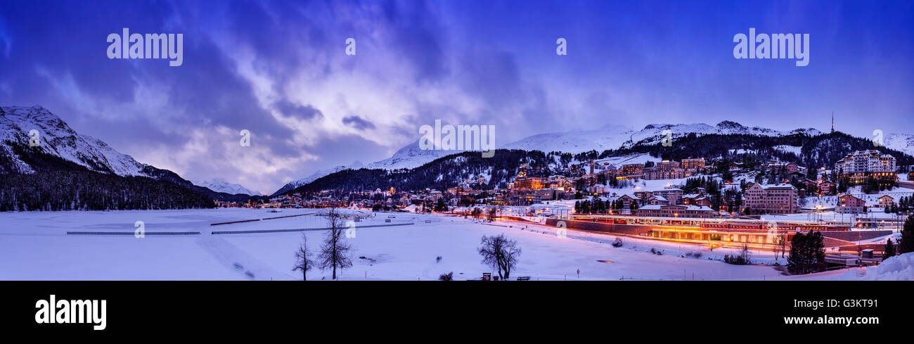 Dorf unter Berg auf verschneite Landschaft beleuchtet am Abend, Sankt Moritz, Schweiz Stockfoto