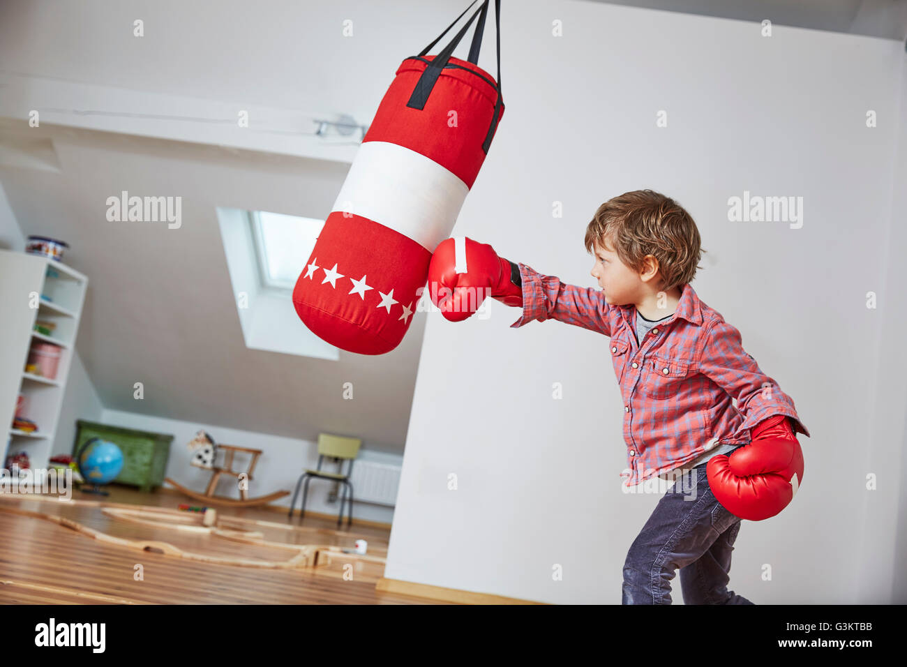 Jungen tragen Boxhandschuhe Boxsack Stanzen Stockfoto