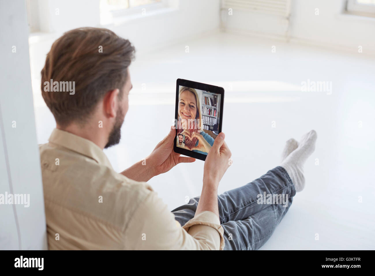 Junger Mann am Boden im Gespräch mit Freundin auf digital-Tablette Videoanruf Stockfoto