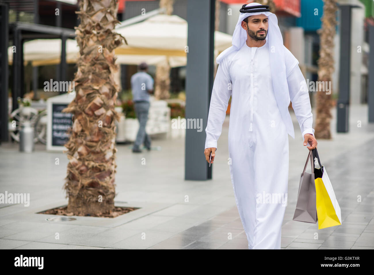 Mann trägt traditionelle orientalische Kleidung zu Fuß entlang der Straße  Shopping Tragetaschen, Dubai, Vereinigte Arabische Emirate Stockfotografie  - Alamy