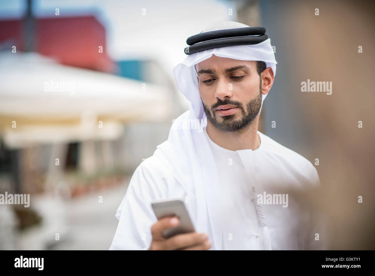 Mann trägt traditionellen orientalischen Kleidung lesen Smartphone Text, Dubai, Vereinigte Arabische Emirate Stockfoto