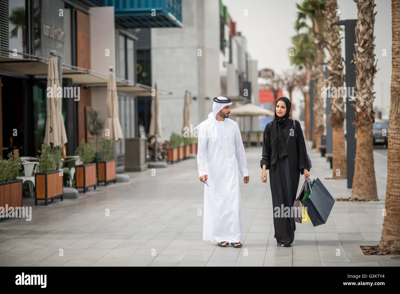 Nahen Ostens shopping paar tragen traditionelle Kleidung, Einkaufstaschen, Dubai, Vereinigte Arabische Emirate Stockfoto