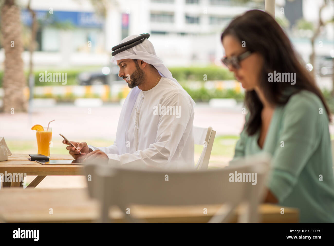 Nahen Ostens Mann tragen traditionelle Kleidung lesen Smartphone Text im Café, Dubai, Vereinigte Arabische Emirate Stockfoto