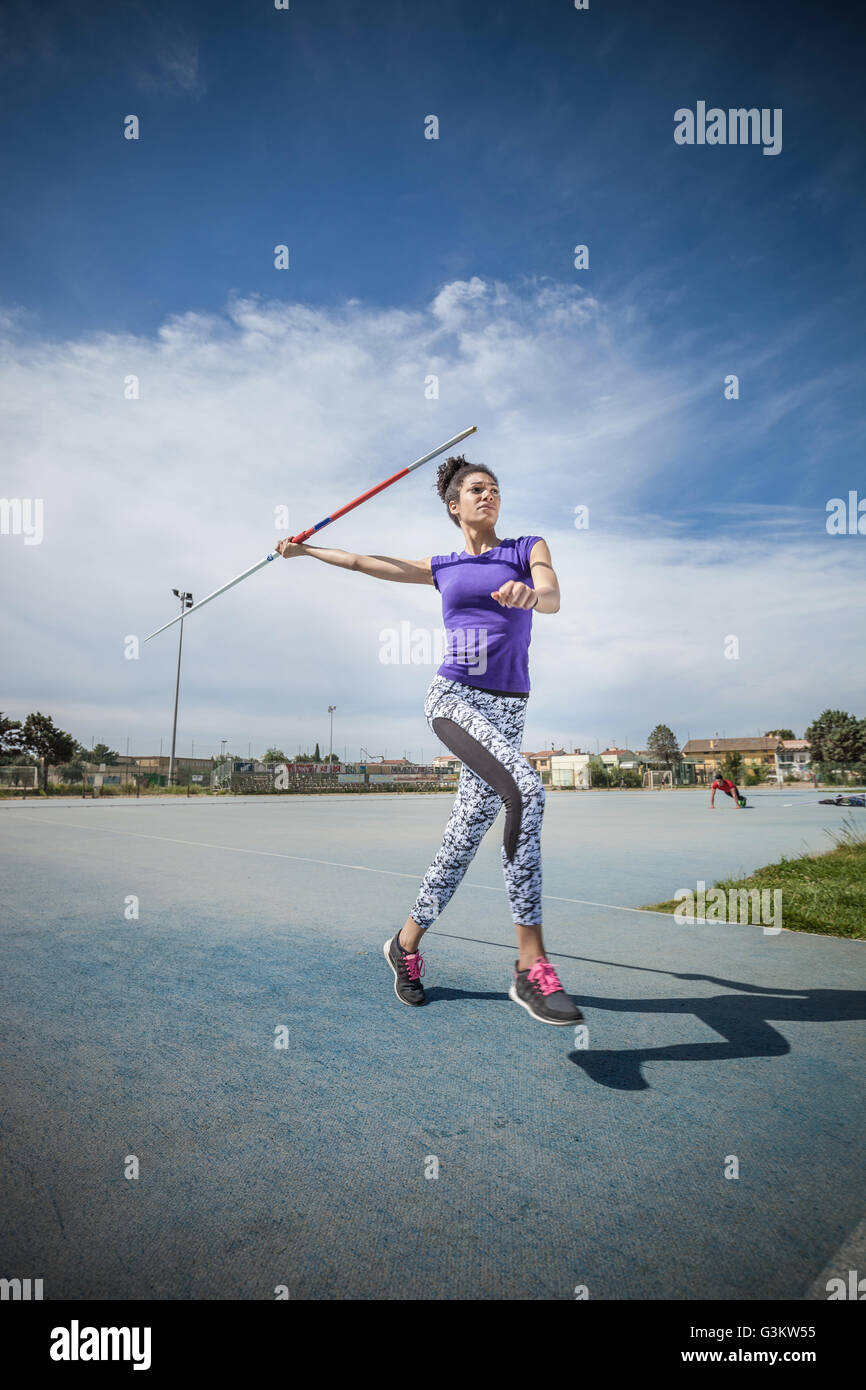 Junge Frau wirft Speer in Sportplatz Stockfoto