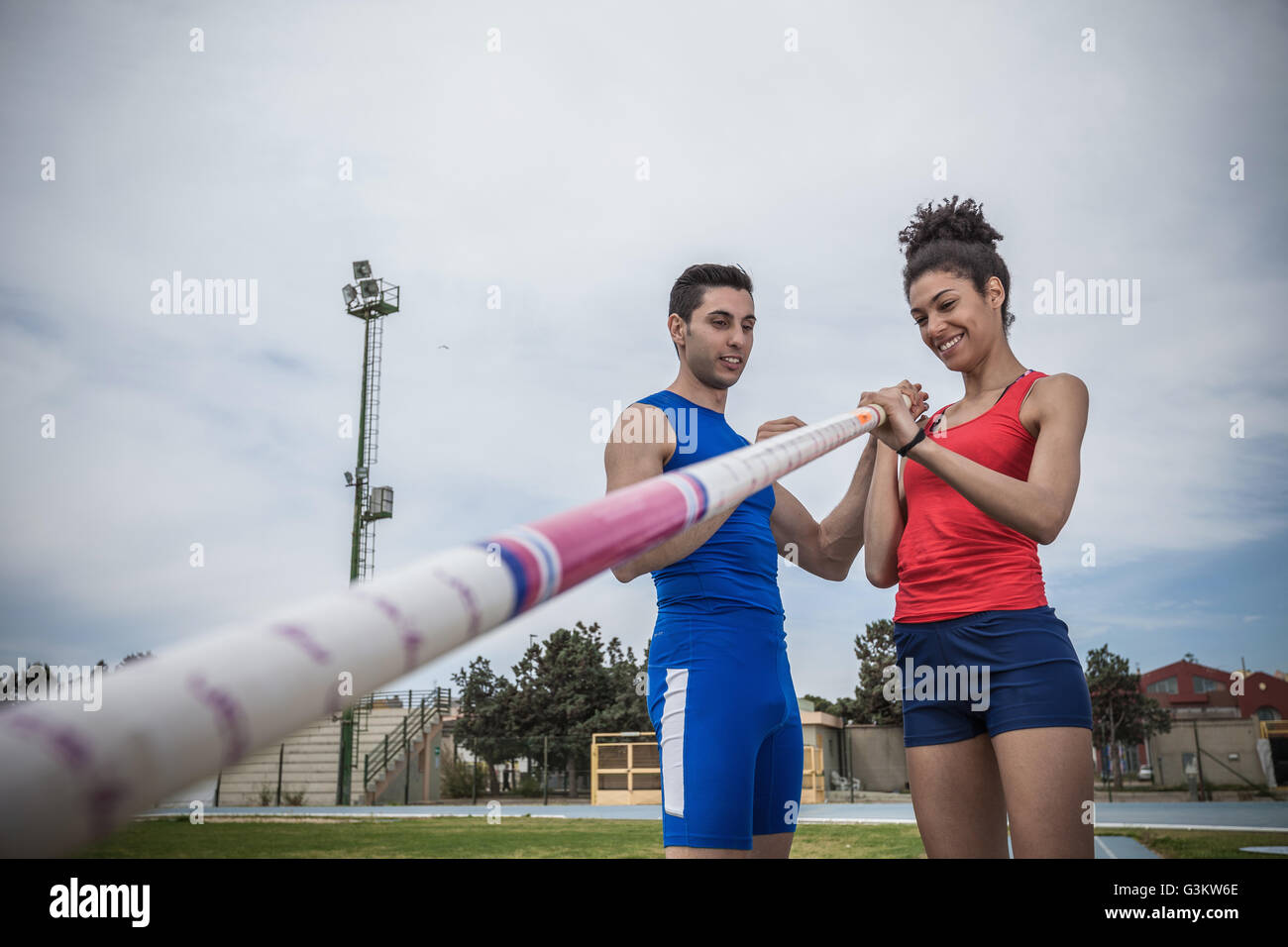 Mann belehren junge weibliche Stabhochspringer bei Sportanlage Stockfoto